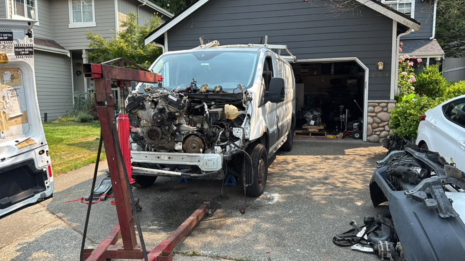 Van engine removed with an engine hoist in a driveway