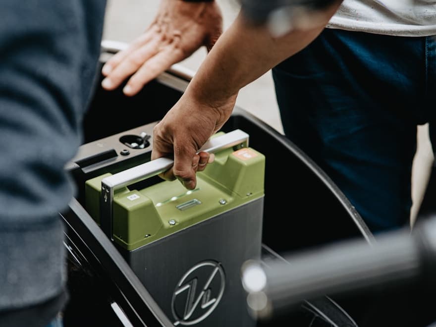 Mechanic lifting a car battery out of an engine bay