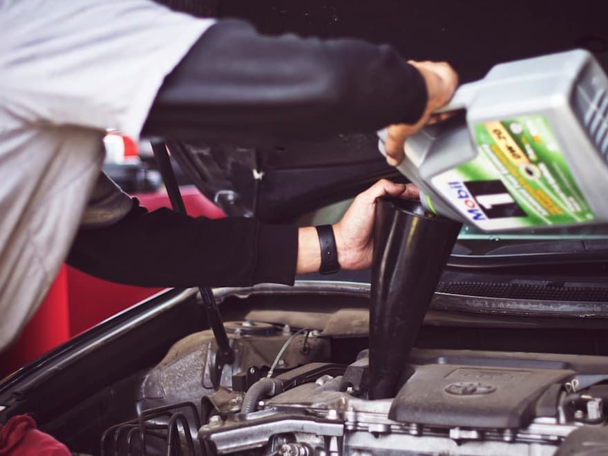 Fresh engine oil being poured during an oil change